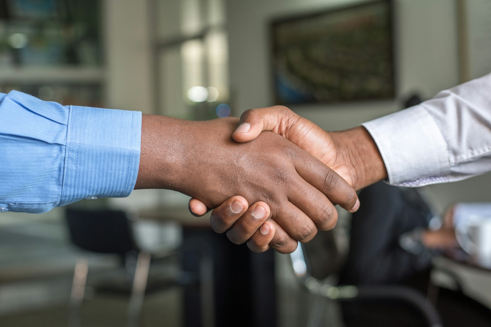 Two people shaking hands across a desk after a settlement